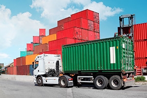 Cargo Containers piled high on vessel with freight truck.